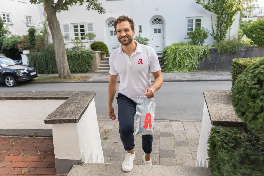 Ein Mitarbeiter der Neutorapotheke Dortmund bringt eine Tüte mit Medikamenten zum Patienten nach Hause