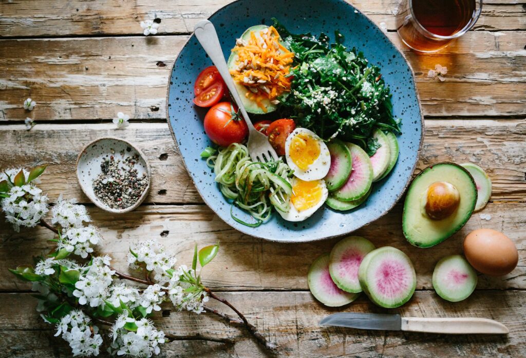 foto eines gesunden essens bestehend aus ei, salat und avocado in einem blauen teller auf einem holztisch der neutor apotheke dortmund