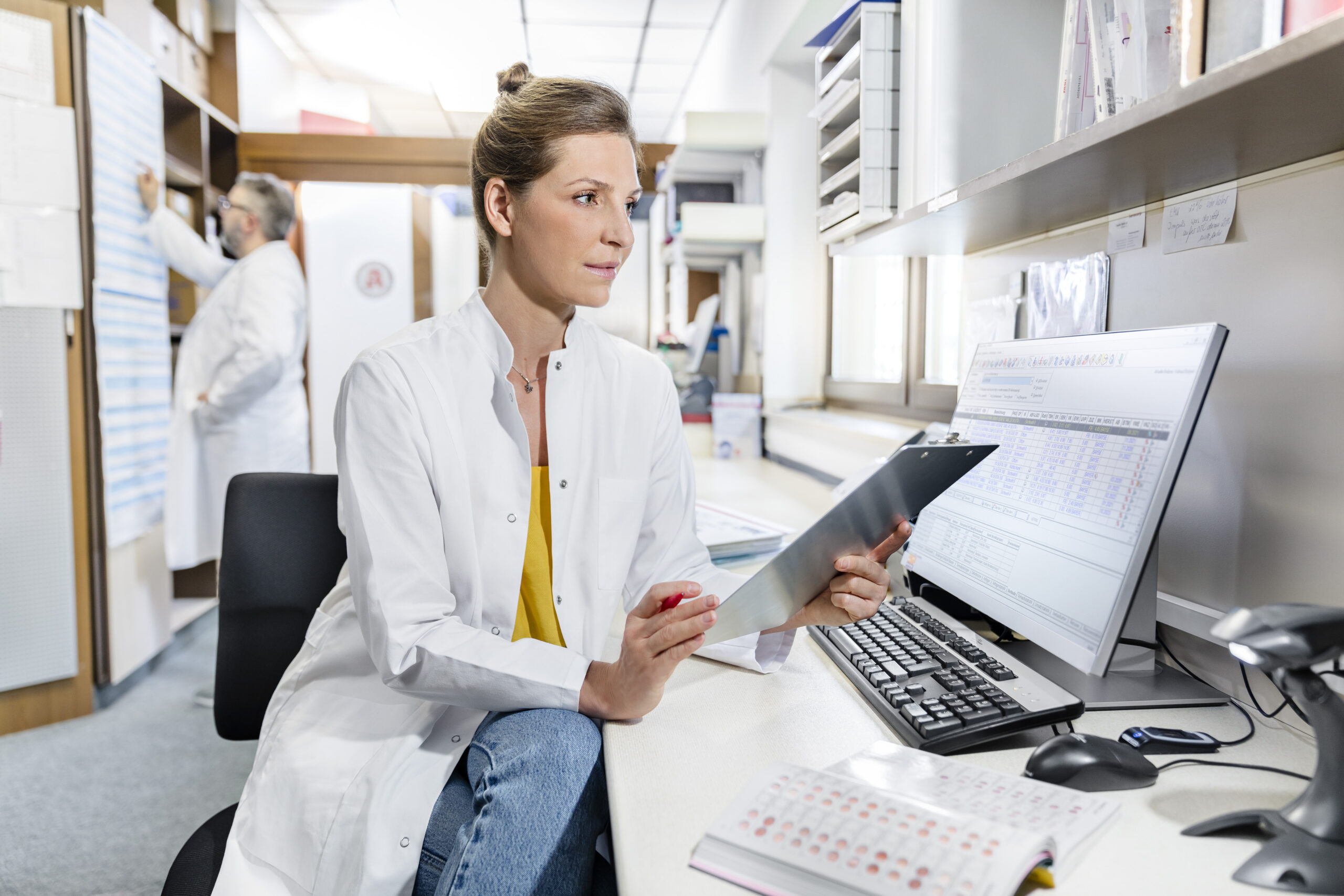 EIne Mitarbeiterin der Neutor Apotheke Dortmund prüft im Backoffice mit einem Klemmbrett die bestellten Medikamente der Kundin.