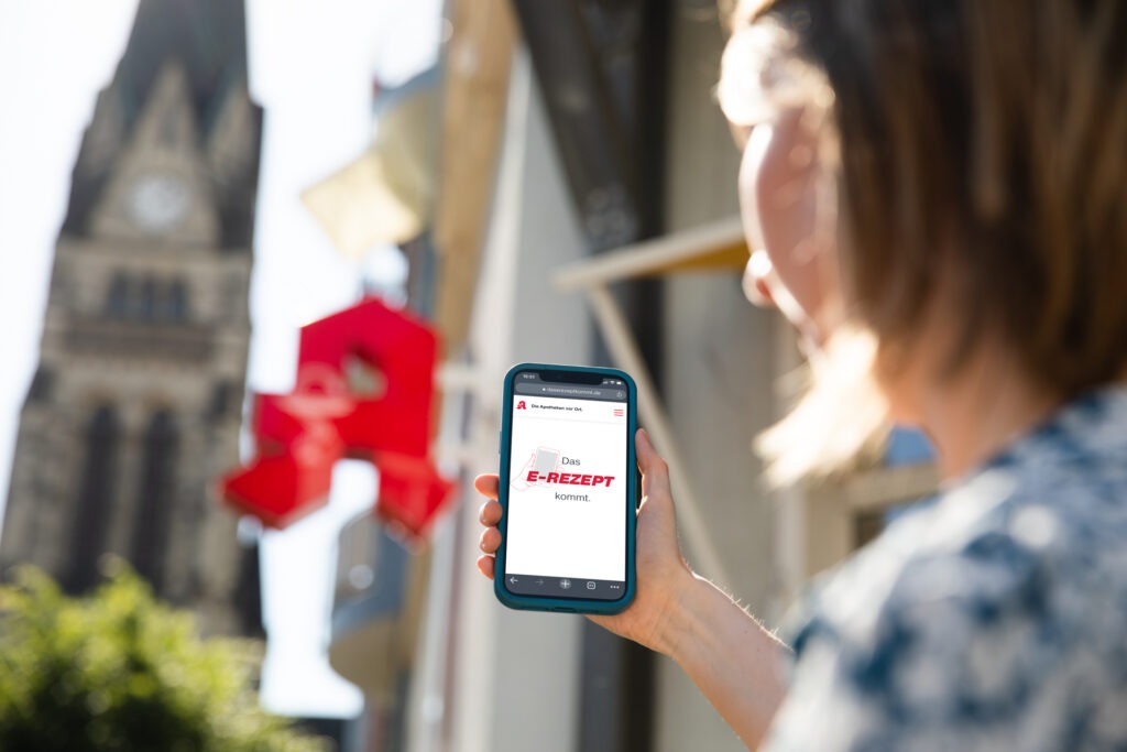 Eine Frau hält ein Smartphone zur Terminbuchung in der Neutor Apotheke Dortmund hoch