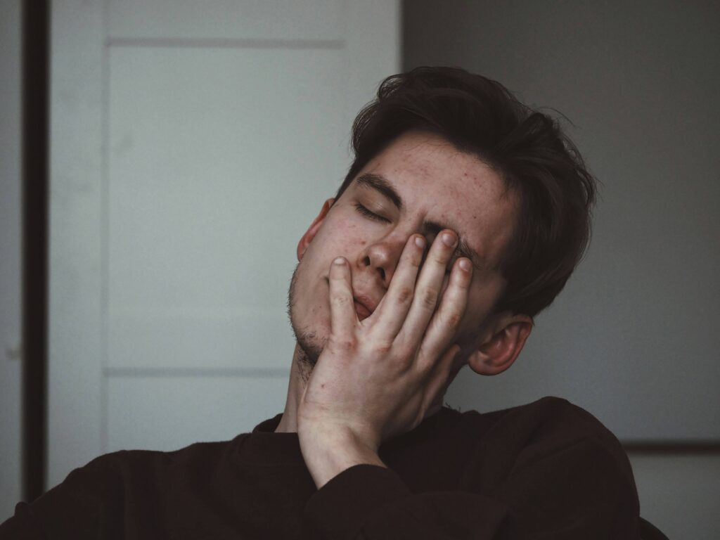 Ein junger Mann reibt sich erschöpft die Augen. Unerklärliche Müdigkeit ist ein typisches frühes Anzeichen für Diabetes.