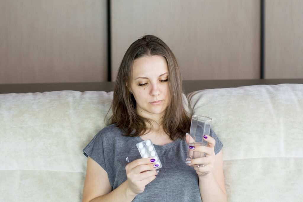 Eine kranke Frau betrachtet eine Tablettenpackung. Eine erhöhte Infektanfälligkeit zählt zu den frühen Warnsignalen bei Diabetes.