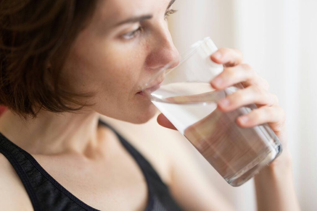 Eine Frau trinkt ein großes Glas Wasser. Ein extrem starkes Durstgefühl ist ein klassisches Frühsymptom für Diabetes.